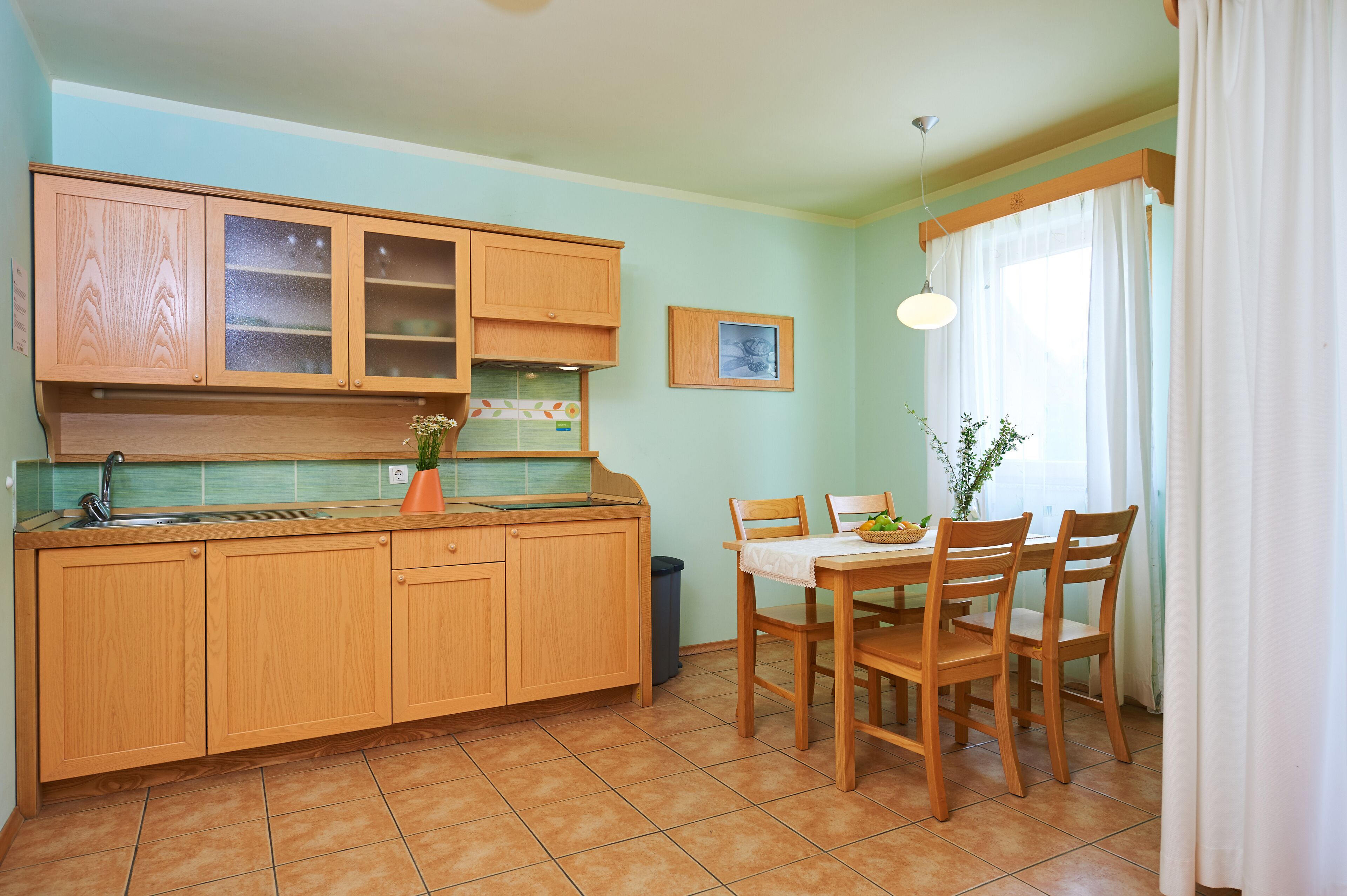 A kitchen with wooden cabinets, a sink, and a dining table with chairs.