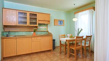 A kitchen with wooden cabinets, a sink, and a dining table with chairs.