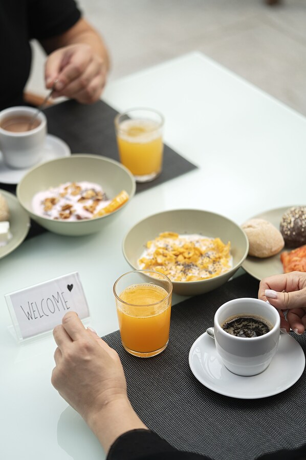 A breakfast setting with various dishes, a cup of coffee, and a glass of orange juice on a table. - Hotel Urban Estação (Braga)