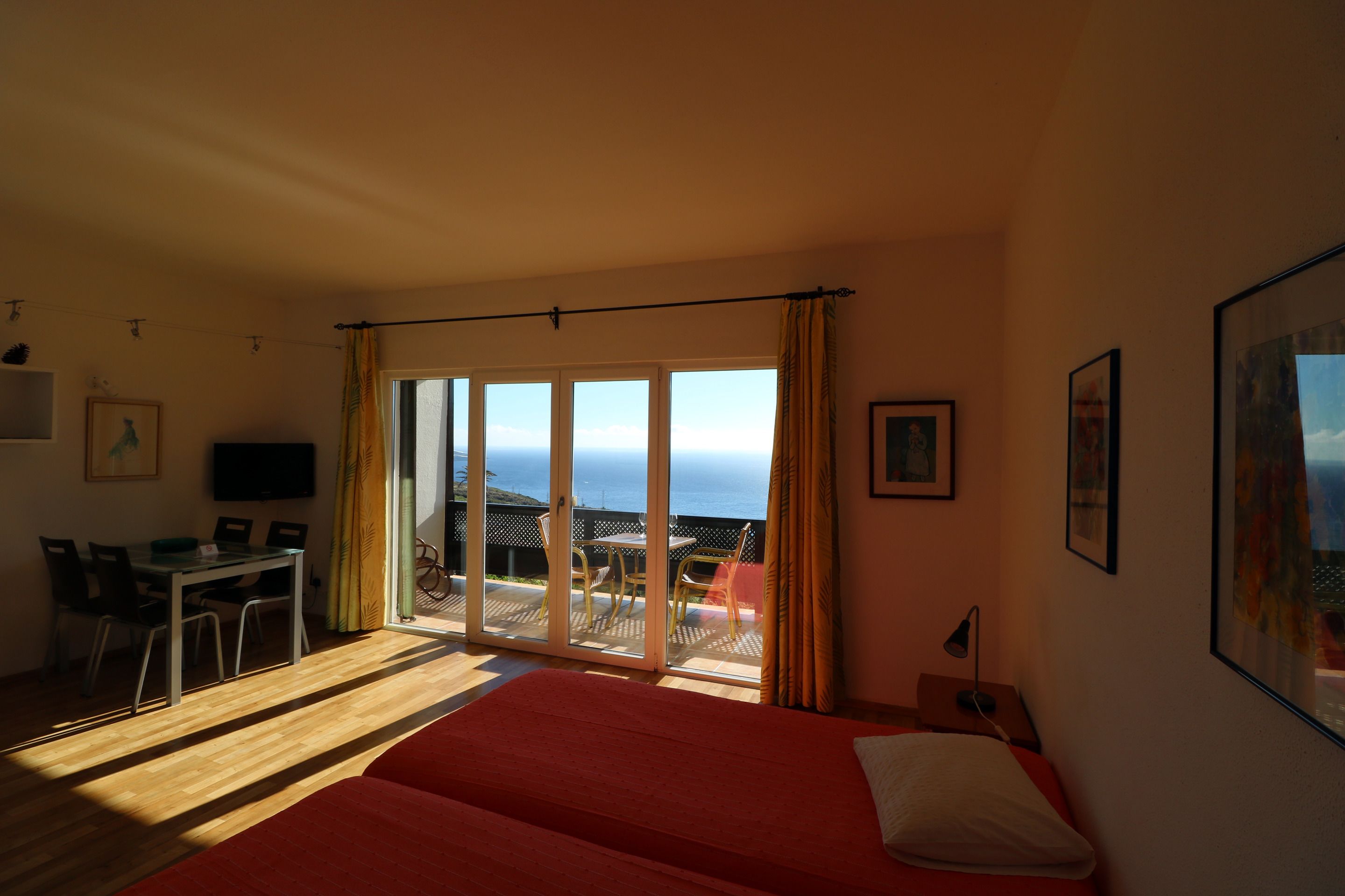 A room with a bed, a desk, and a view of the ocean.