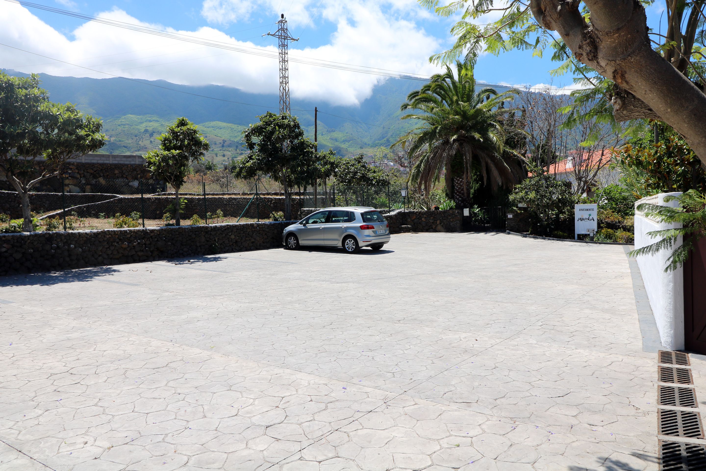 A parking area with a car, stone walls, and a view of mountains.