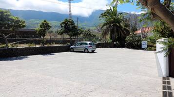 A parking area with a car, stone walls, and a view of mountains.