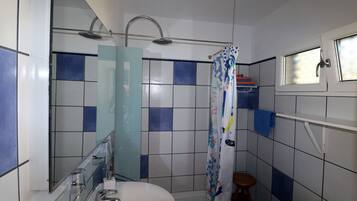 Een badkamer met een douche, toilet en wastafel.