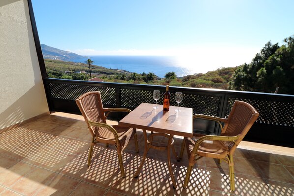 A balcony with a table and chairs, a bottle, and glasses. - Apartamentos Miranda (Brena Alta)