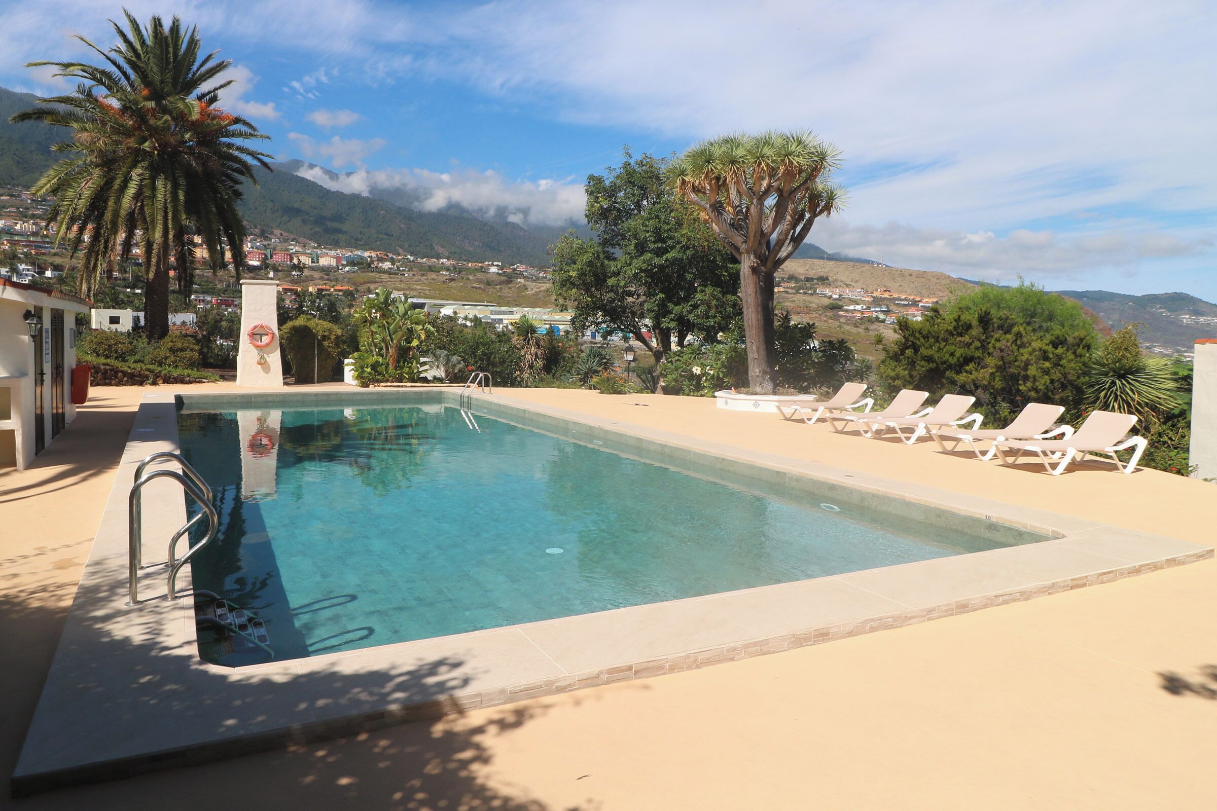 A swimming pool with a view of a town and mountains in the background.