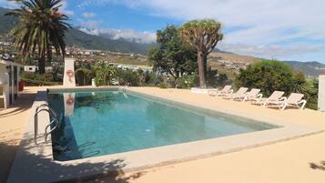 A swimming pool with a view of a town and mountains in the background.