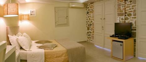 A bedroom with a bed, a television on a stand, a wardrobe, and a small cabinet.