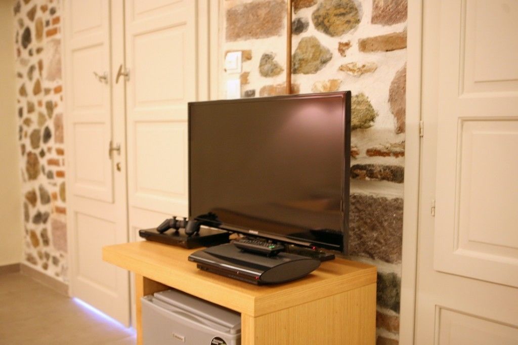 A television on a wooden stand with a remote control and a game controller.