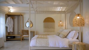 Een slaapkamer met een bed, een houten stoel, een nachtkastje, een hanglamp en een spiegel aan de muur.