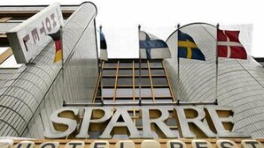 The exterior of a hotel named SPARRE HOTEL REST with a modern design, featuring a prominent sign and multiple flags.