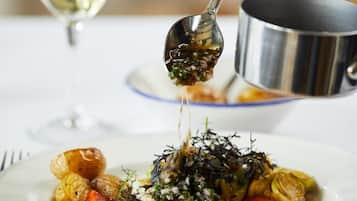 A plate of food with a spoon pouring sauce over it.