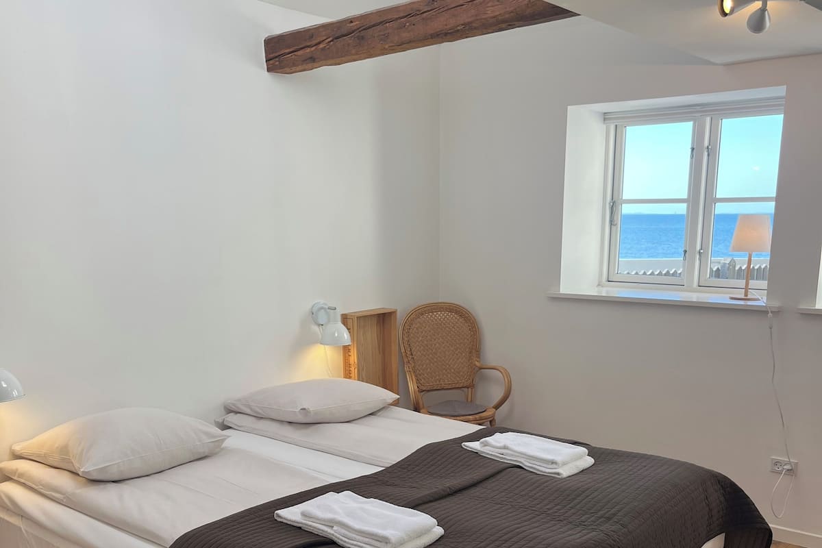 A bedroom with a bed, a chair, a window with a view, and a ceiling light.