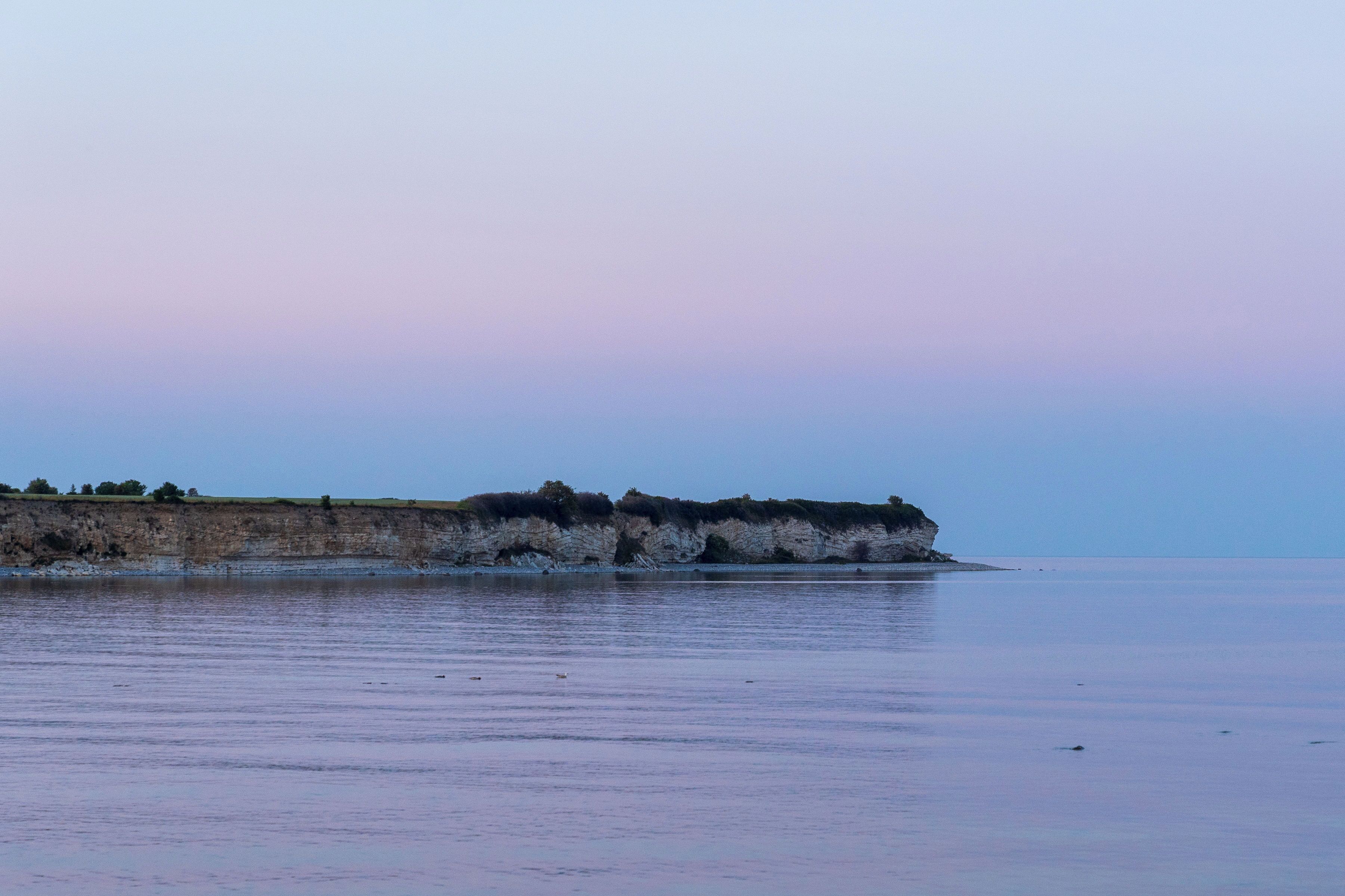 A coastal landscape with a cliff and calm water.
