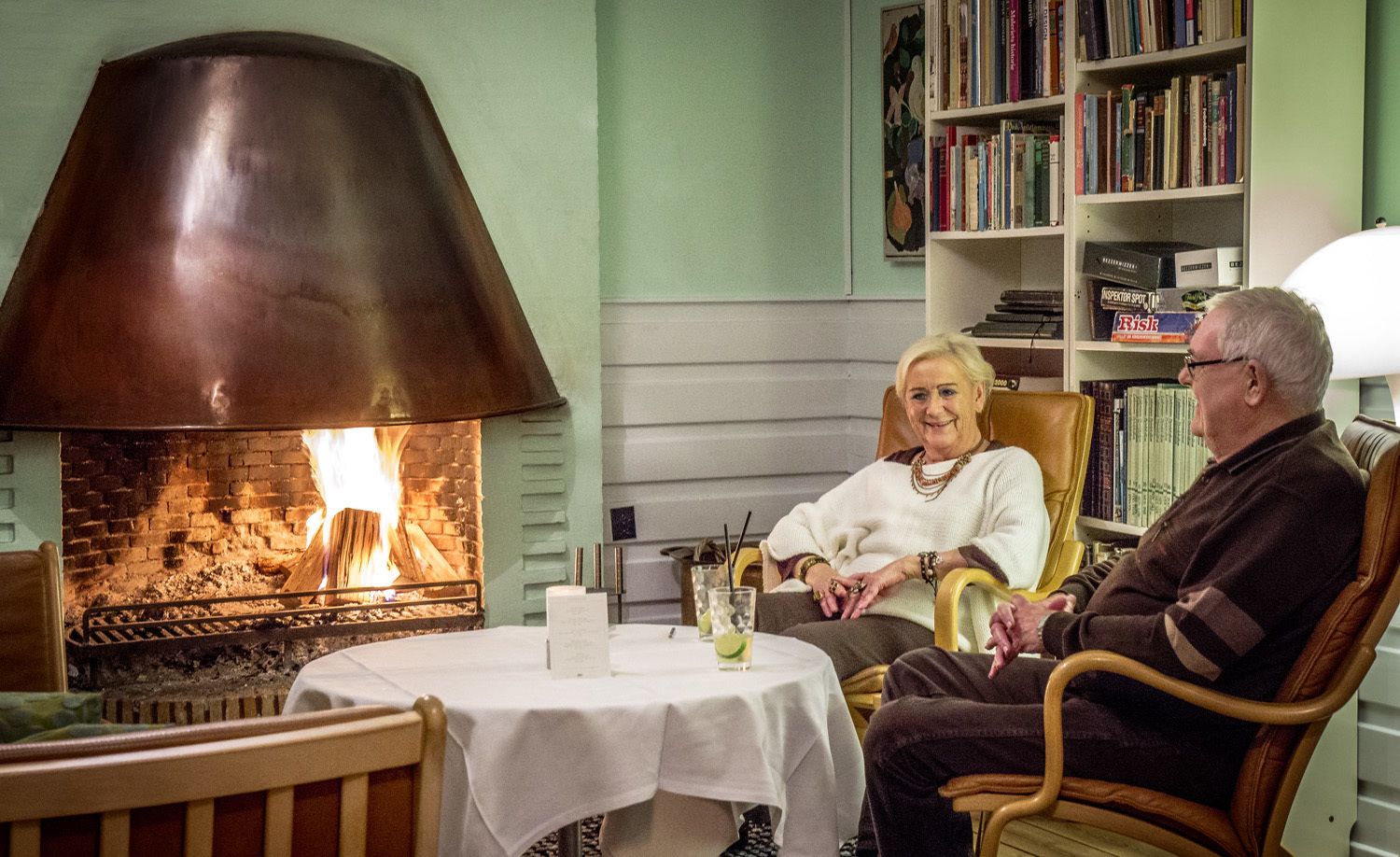 Una habitación acogedora con chimenea, una mesa con bebidas y una estantería.