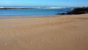 Una playa con cielos despejados y aguas tranquilas.