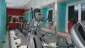 Un gimnasio con varias máquinas de ejercicio, suelo de baldosas y pared roja.