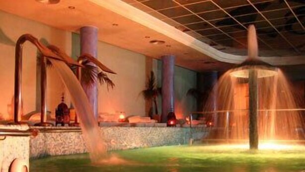 Un espacio de spa con fuente de agua, asientos de piedra e iluminación ambiental.
