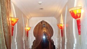 Un pasillo con alfombra roja, paredes blancas y una escalera de madera.