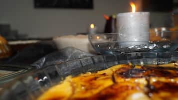 Une bougie posée sur un plateau en verre, avec des aliments, peut-être un dessert, dans une pièce à la lumière tamisée.