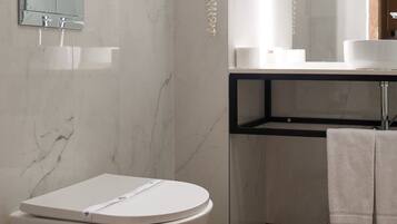 A modern bathroom with a freestanding toilet, a built-in sink, and a large mirror.