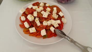A plate of tomato salad with feta cheese and herbs.