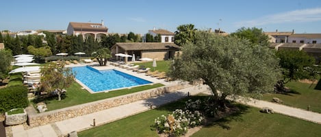 A residential property with a swimming pool, outdoor seating, and a well-maintained lawn.