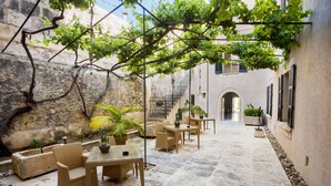 An outdoor patio with wicker furniture, stone flooring, and potted plants.