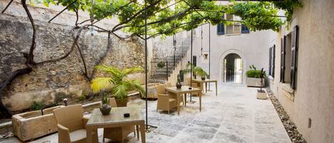 An outdoor patio with wicker furniture, stone flooring, and potted plants.