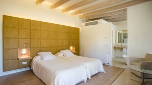 A modern bedroom with two beds, a glass table, and a wooden ceiling.