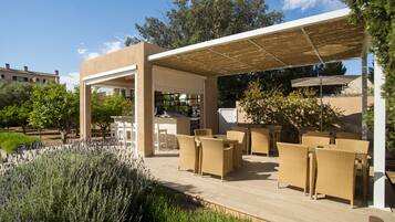 An outdoor patio with wicker furniture, a pergola, and a view of the surrounding landscape.