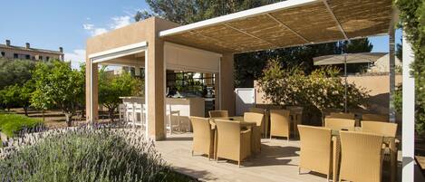 An outdoor patio with wicker furniture, a pergola, and a view of the surrounding landscape.