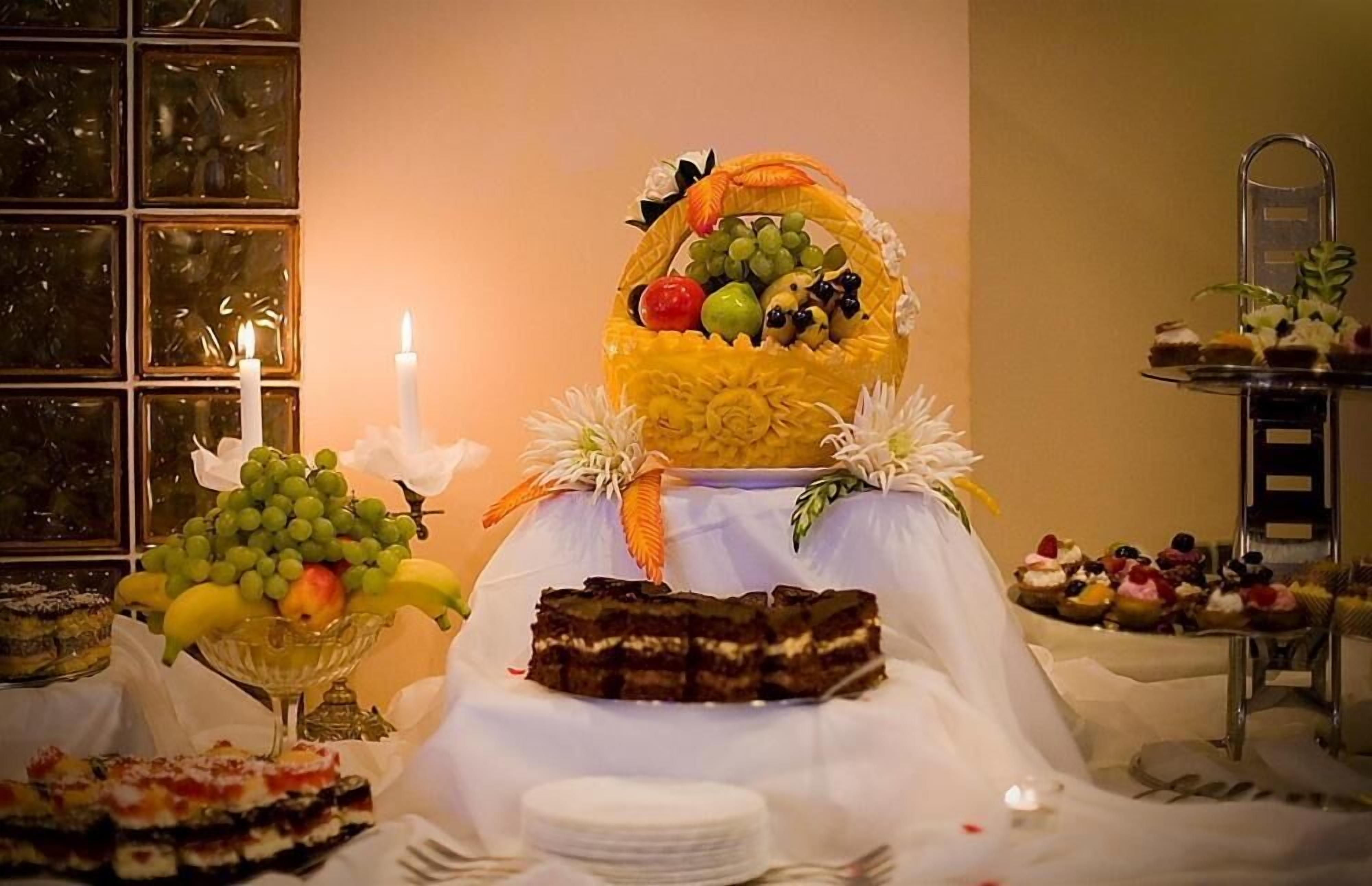 A buffet table with various desserts and a fruit basket.