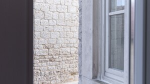 Una ventana con vista a un edificio de piedra y un persiano verde.