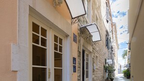 Un estrecho callejón con un edificio que tiene una puerta blanca grande y una ventana pequeña.