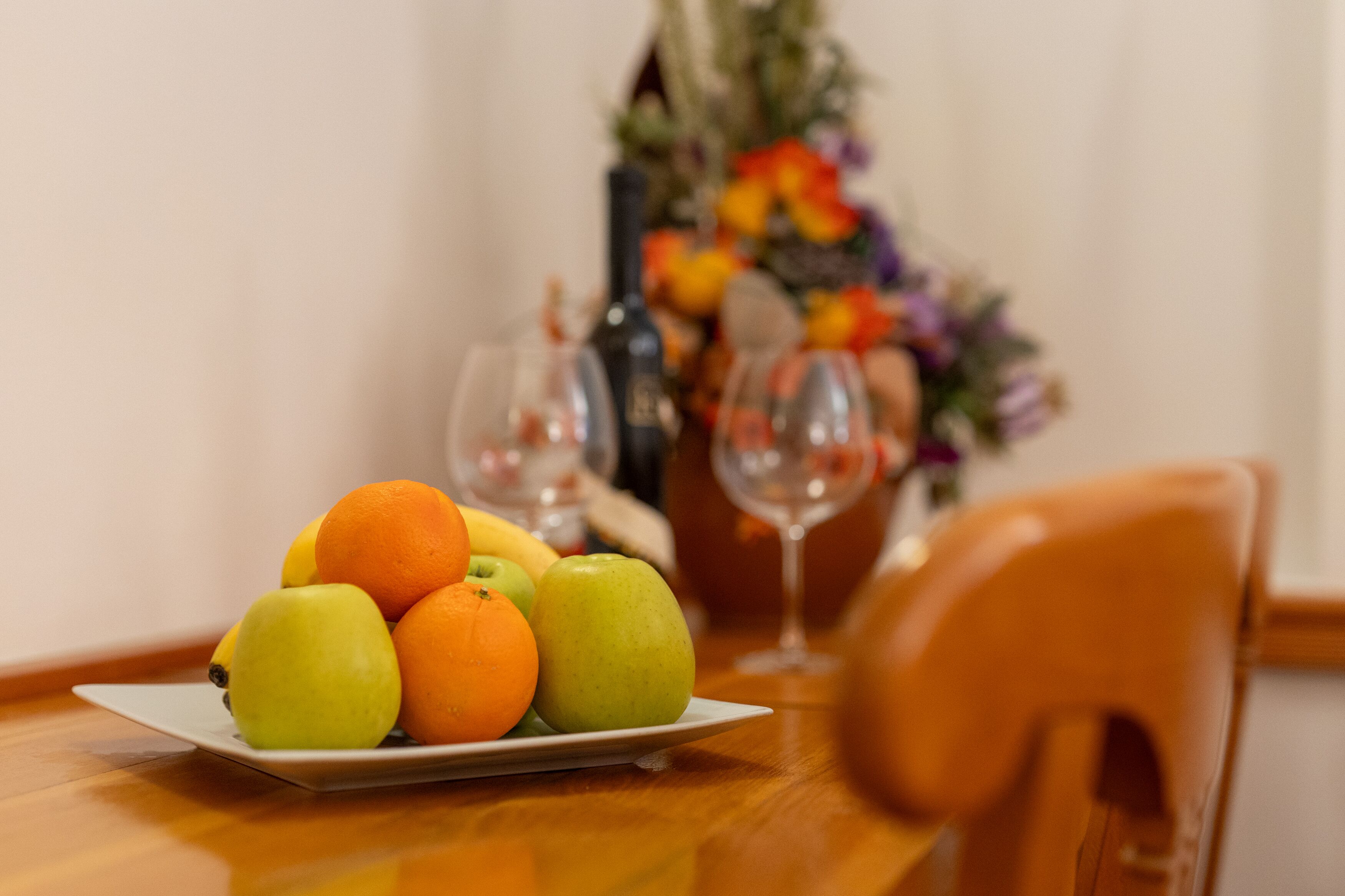 A table with a plate of fruit and two wine glasses.