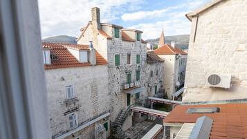 A narrow street with stone buildings, a visible staircase, and a clear sky.