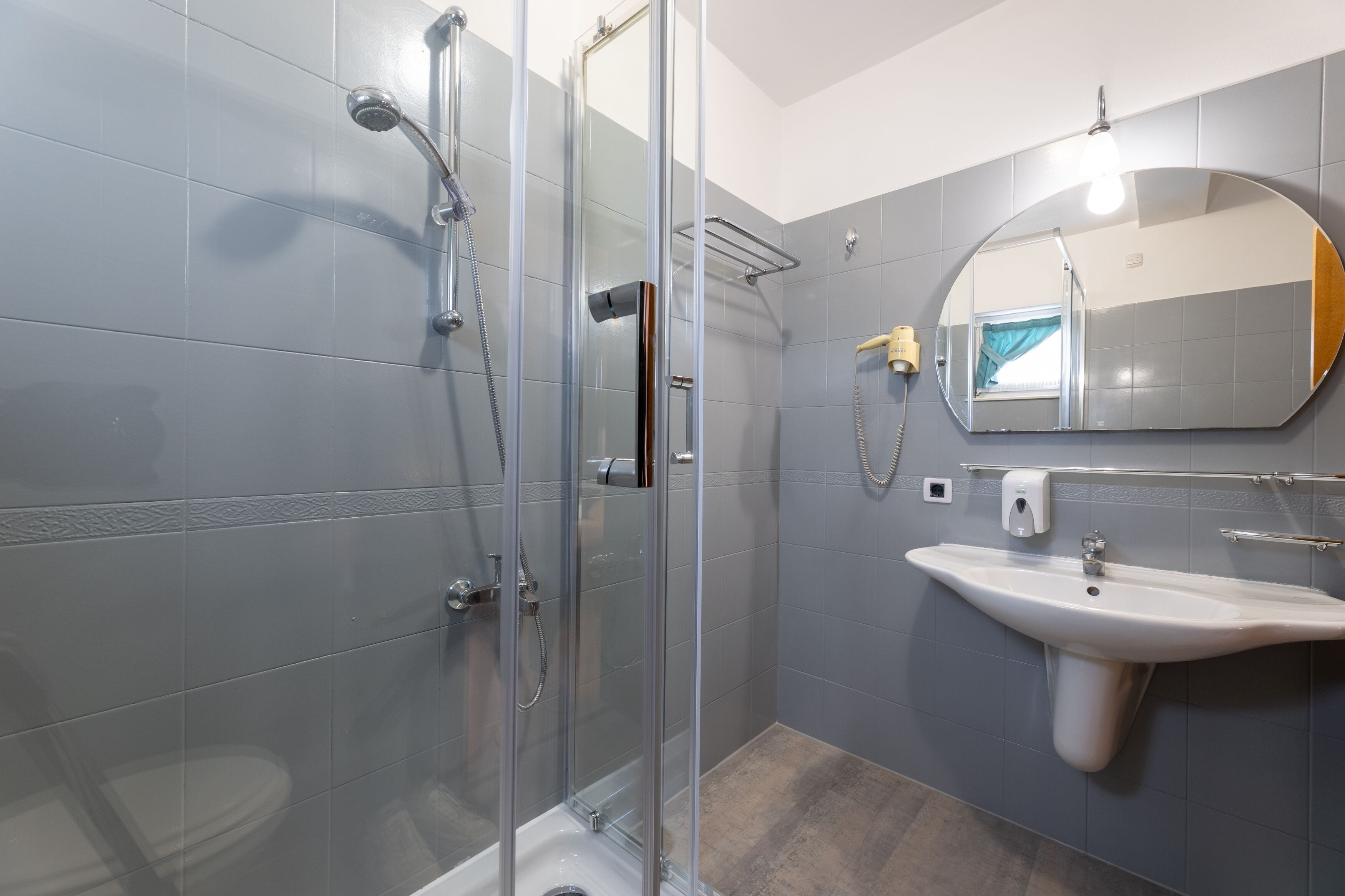 Een moderne badkamer met een douchecabine van glas, een wastafel en een spiegel.