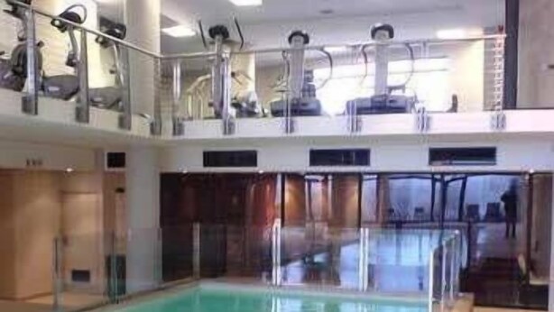 Ein Hallenbad mit klarem Wasser, Glastrennvorrichtungen und gefliestem Boden.