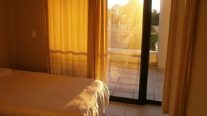 Ein Hotelzimmer mit Bett, Vorhängen und einer Schiebeglastür, die zu einem Außenbereich führt.
