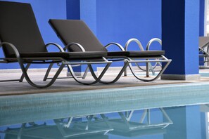 A poolside area with lounge chairs and a clear pool.