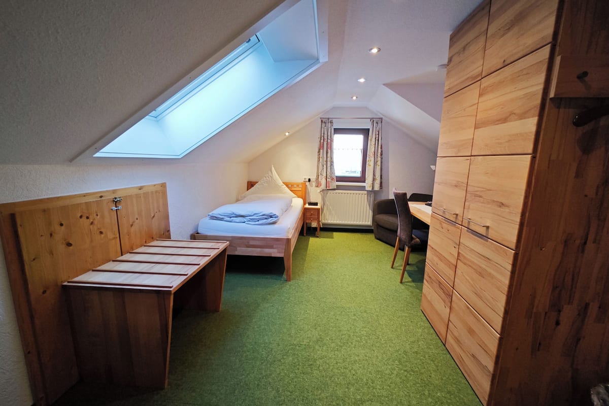 Quarto compacto com beliche, escrivaninha e tapete verde.