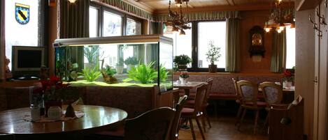 A restaurant with wooden furniture, a fish tank, and a clock on the wall.