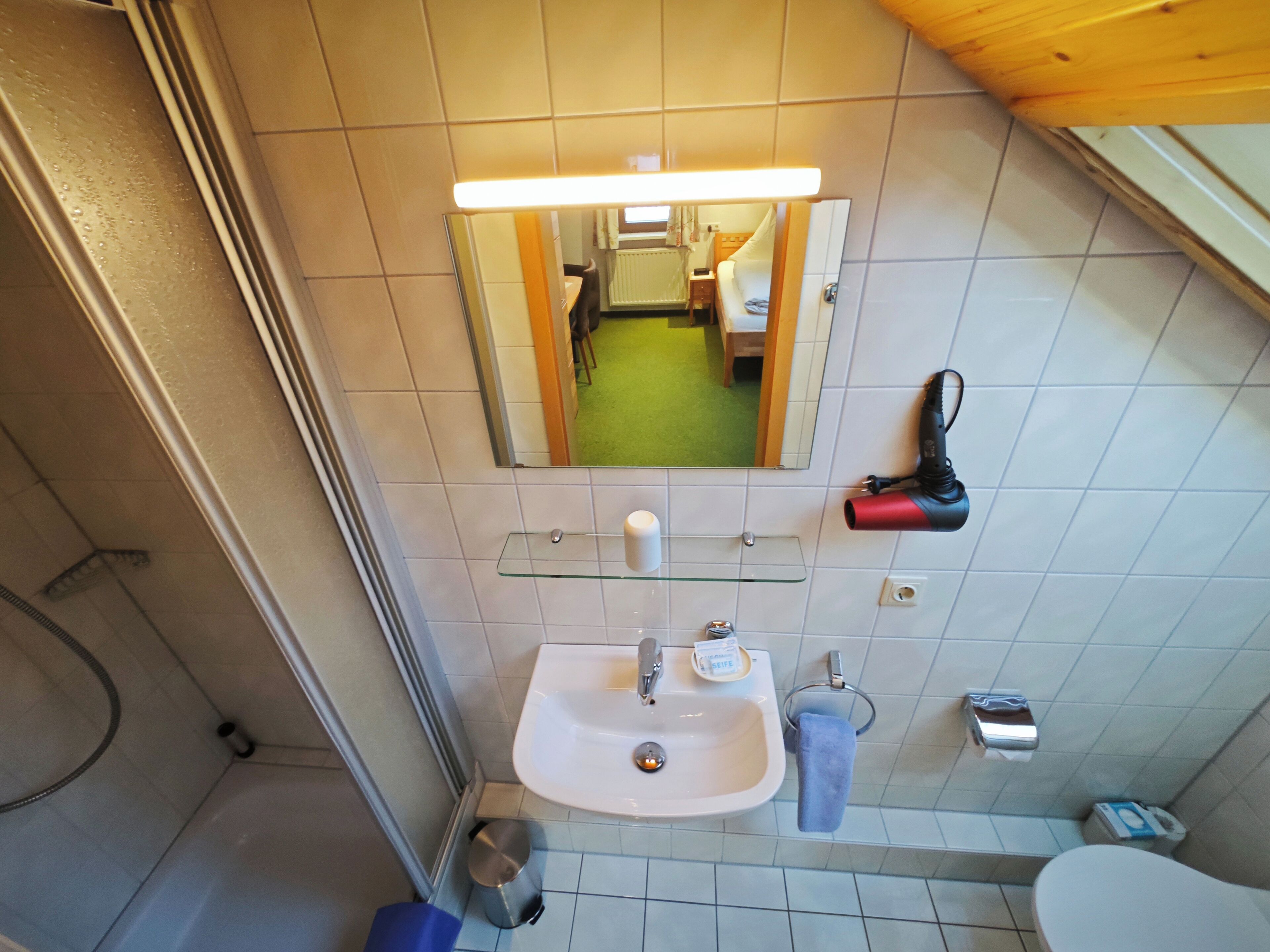 A bathroom with a sink, mirror, and a hairdryer on the wall.
