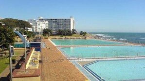 Un vaste espace extérieur doté d’une grande piscine, de plusieurs bassins, d’une plage de sable et d’une vue sur l’océan.