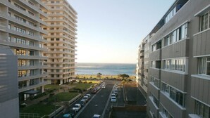 Un immeuble de grande hauteur, avec de nombreux étages, un parking à l’avant et une vue sur l’océan.