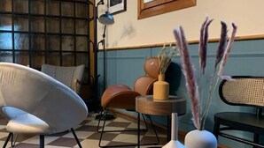 A modern interior with a checkered floor, a white chair, a round table, and a vase with pampas grass. - Ristorante Locanda Milano (Gambolo)