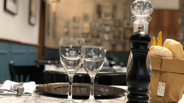 A dining table set with two wine glasses, a salt and pepper shaker, a bread basket, and a plate. - Ristorante Locanda Milano (Gambolo)