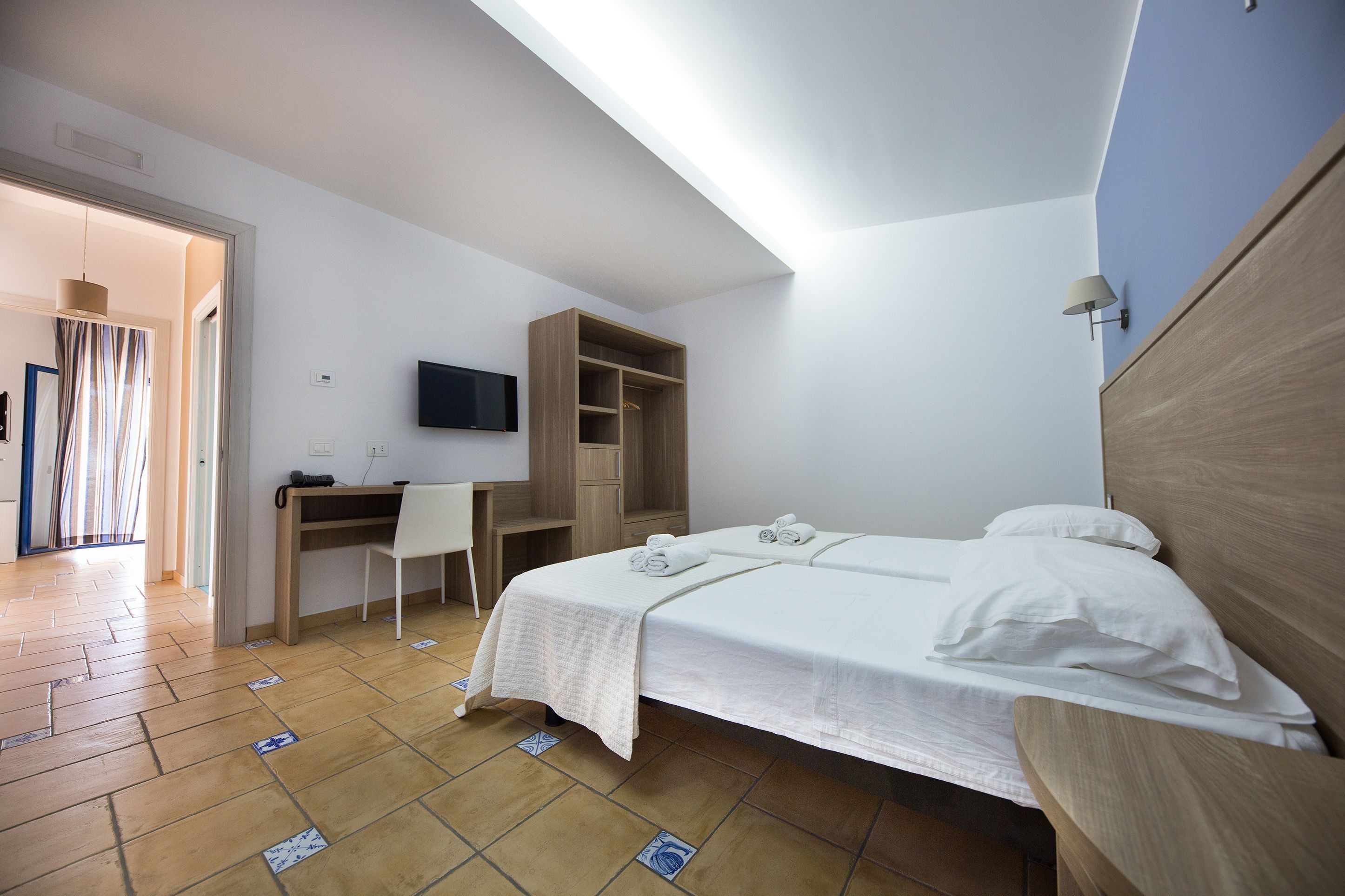 Ein Hotelzimmer mit Bett, Schreibtisch und Fernseher.