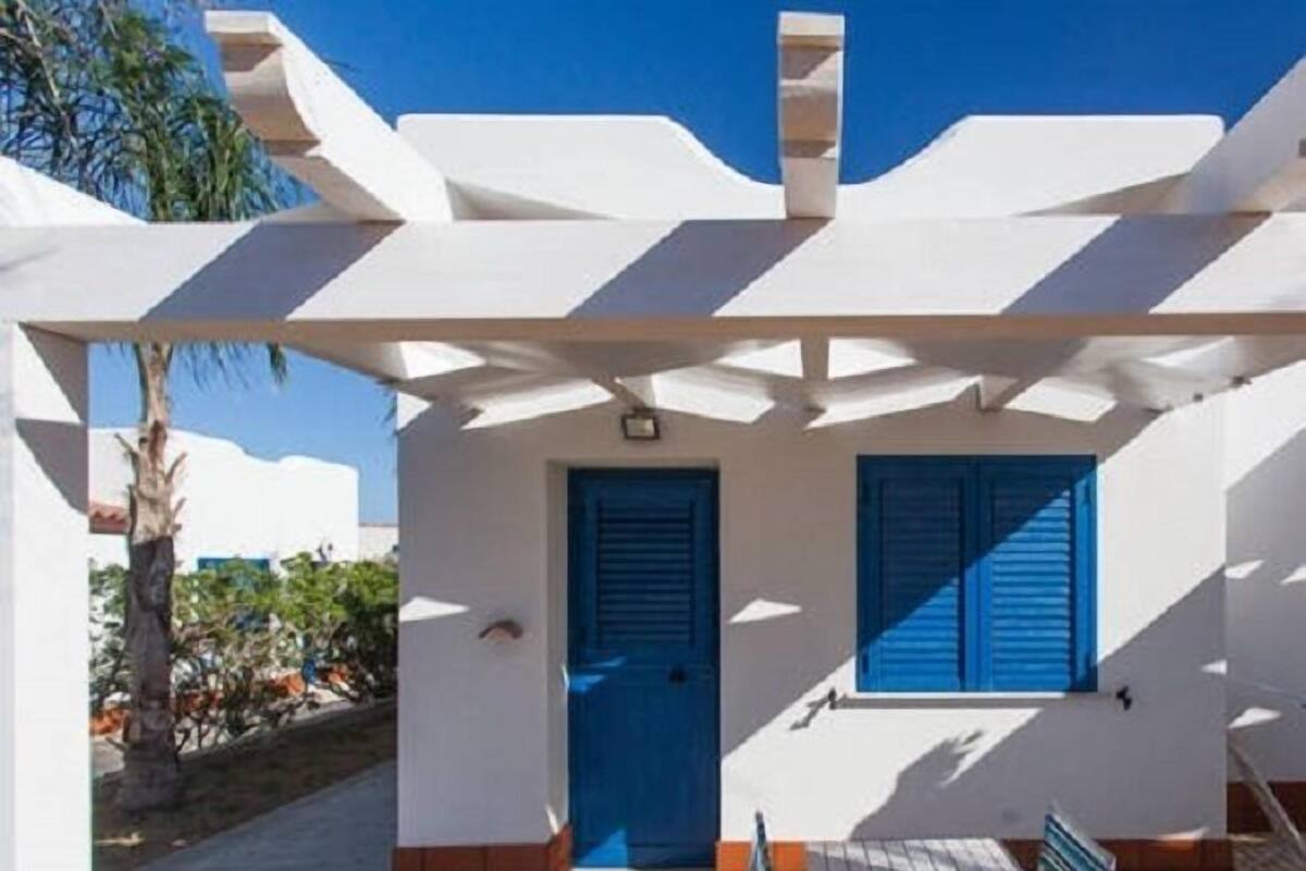 A covered outdoor area with a blue door, a small table, and a chair.
