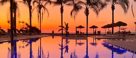 Una piscina al aire libre de temporada, sombrillas